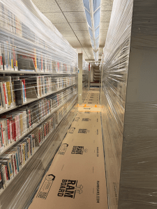 Image of the Adult nonfiction stacks wrapped in plastic, with the floor covered in protective boards. 