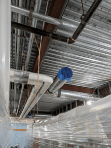 A photo of the ceiling with shiny new pipes visible.